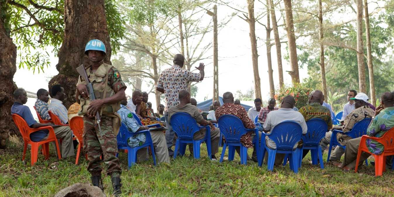 Peace Negotiation under trees accompanied by UN Blue Helmets